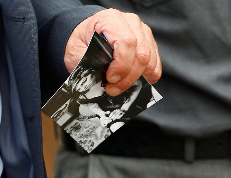 Un asistente al funeral muestra una fotografía de Amy Winehouse