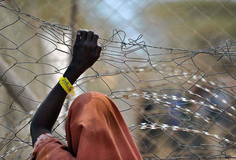 Una persona se apoya en la valla frente a las instalaciones de asistencia médica en Dadaab.