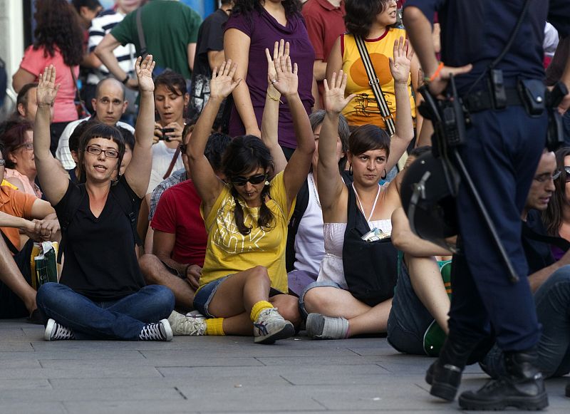 Demonstrators raise their arms as they sit during a protest before Spanish National Police officers removed them from Madrid's Puerta del Sol square