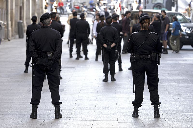 Varios policías municipales, ante el grupo de "indignados" que pasó la noche en la Plaza Mayor de Madrid, antes de desalojarlo del lugar y retirarlo a la calle de Toledo.