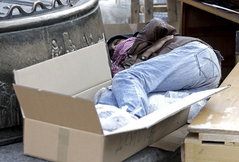 Uno de los acampados duerme entre cartones en la Plaza Mayor de Madrid.