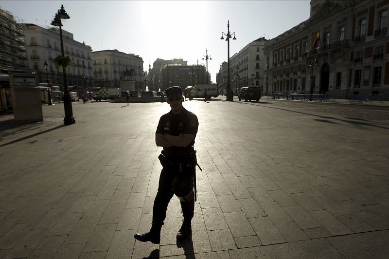 Un policía vigila la Puerta del Sol de Madrid, de donde ayer fueron desalojados los "indignados" que permanecían en el lugar, y cuya estación de Metro ha sido reabierta.