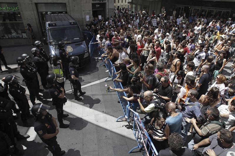 La marcha de "indignados" que partió este mediodía de la plaza de Oriente de Madrid retenida en la calle Preciados donde las vallas y el dispositivo policial impide su acceso a la Puerta del Sol.