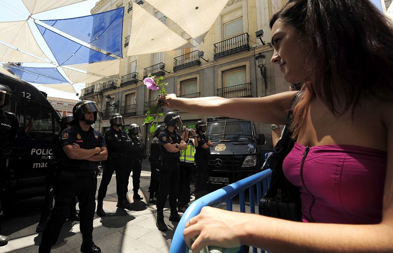 Una manifestante 'indignada' del Movimiento 15M ofrece una flor  a los policías que impiden la entrada en Sol, Madrid.