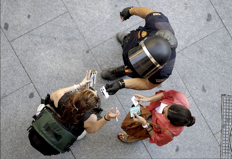 Un agente de Policía requiere la documentación a dos mujeres en un acceso a la Puerta del Sol de Madrid vacía