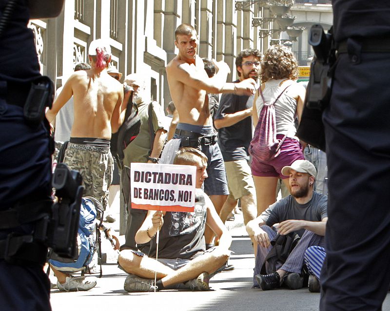 Algunos "indignados" protestas sentados ante el dispositivo policial impide su acceso a la Puerta del Sol, en el marco de la marcha que partió este mediodía desde la Plaza de Oriente