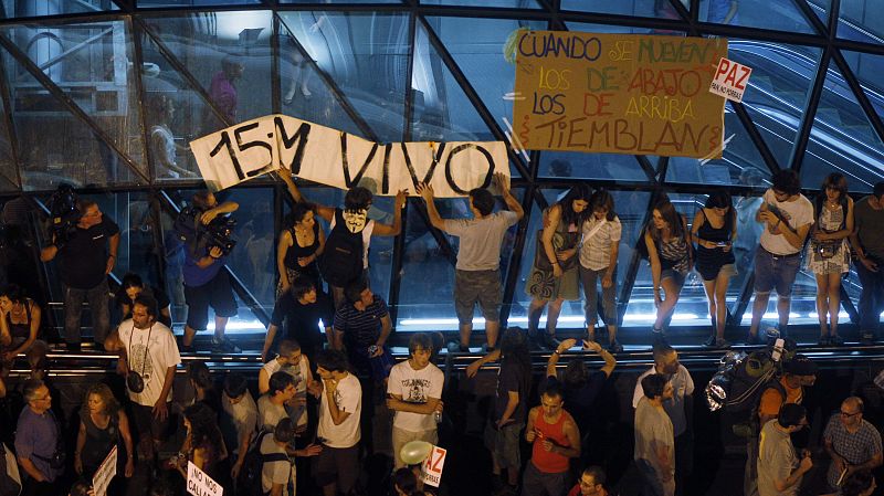 Varios manifestantes colocan una pancarta en la salida del metro de Sol