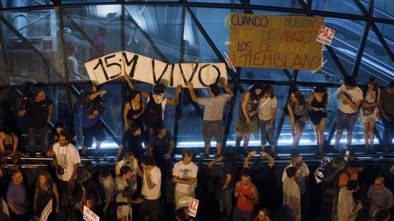 Varios manifestantes colocan una pancarta en la salida del metro de Sol