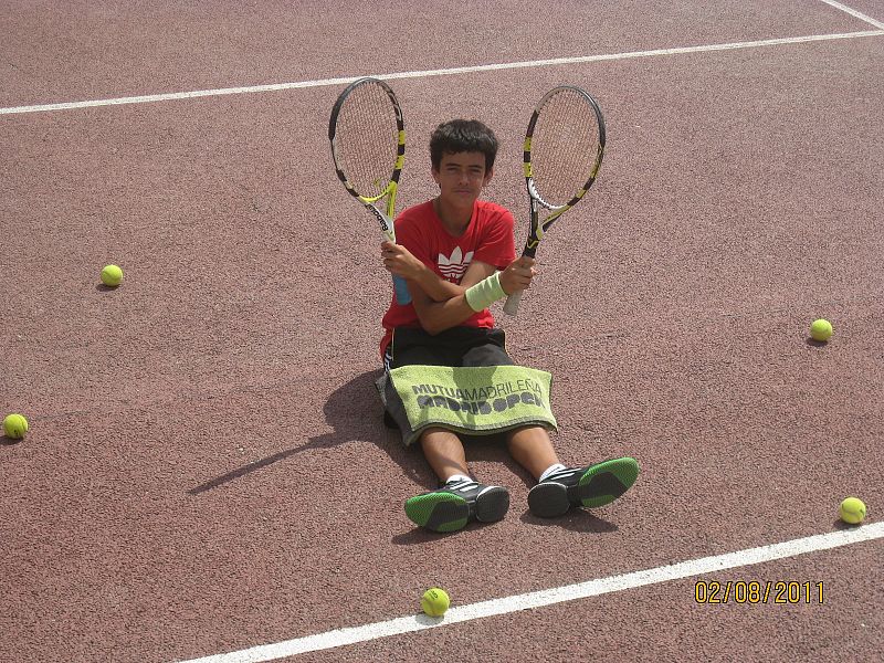 Sentado en la pista , rodeado de pelotas y mis dos raquetas.