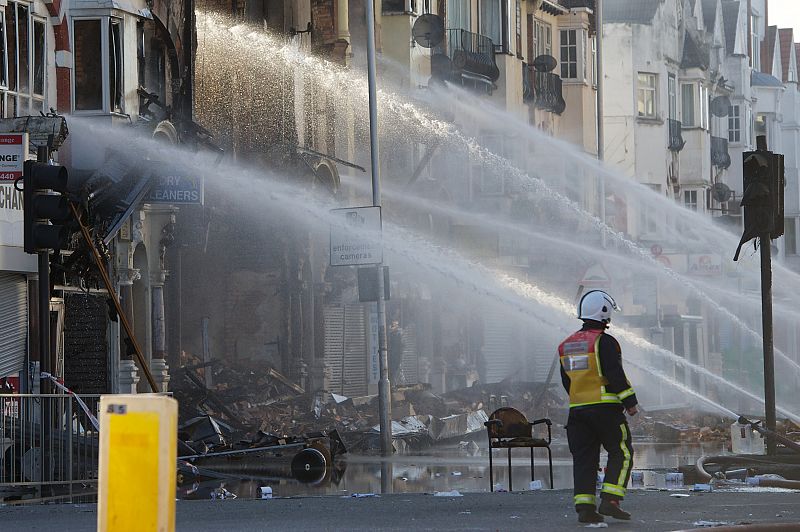 Un equipo de bomberos intentando aplacar el fuego de edificios incendiados.