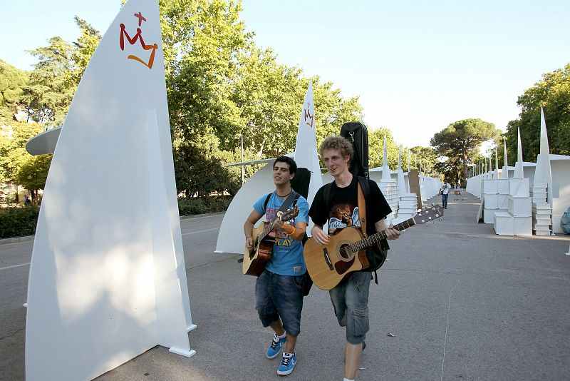 Dos jóvenes pasan junto a algunos de los 200 confesionarios instalados en el parque de El Retiro de Madrid, con motivo de la visita del Papa Benedicto XVI y la Jornada Mundial de la Juventud.