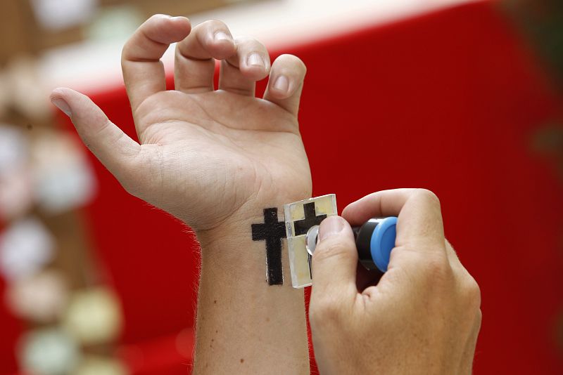 Uno de los visitantes de la exposición fotográfica "Cristianos perseguidos hoy", inaugurada hoy en Madrid por el Nuncio Apostólico en España, Monseñor Renzo Fratini, se estampa en la muñeca el símbolo de la cruz.