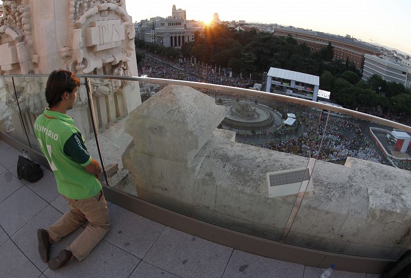 Un voluntario sigue desde un balcón del Ayuntamiento, la misa de bienvenida a los peregrinos de la Jornada Mundial de la Juventud (JMJ)