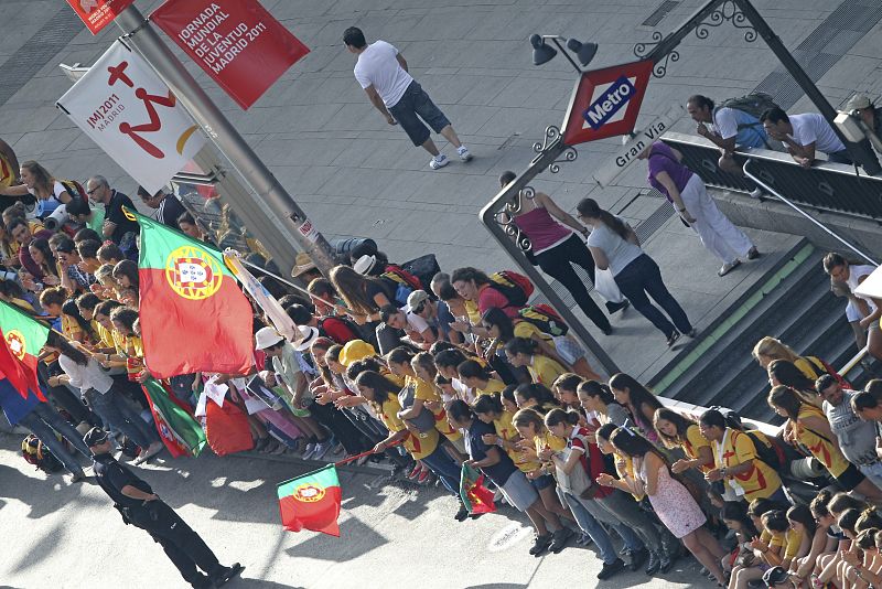 Gran número de personas junto a algunas banderas de Portugal, esperan en la Gran Vía de Madrid, el paso del papa Benedicto XVI durante el recorrido que ha realizado hasta la catedral de La Almudena