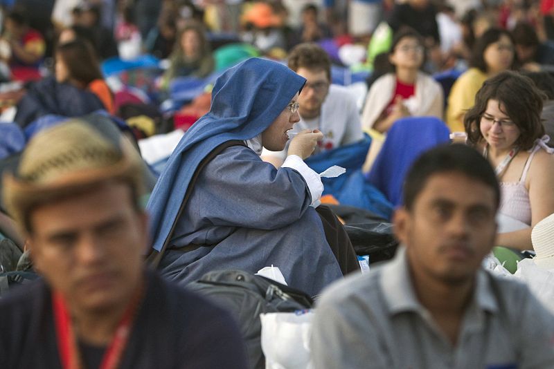 Una religiosa desayuna entre gran número de peregrinos que esperan la llegada del papa Benedicto XV