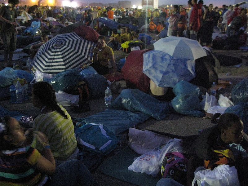 Los peregrinos se resguardan de la lluvia como pueden en la explanada de Cuatro Vientos