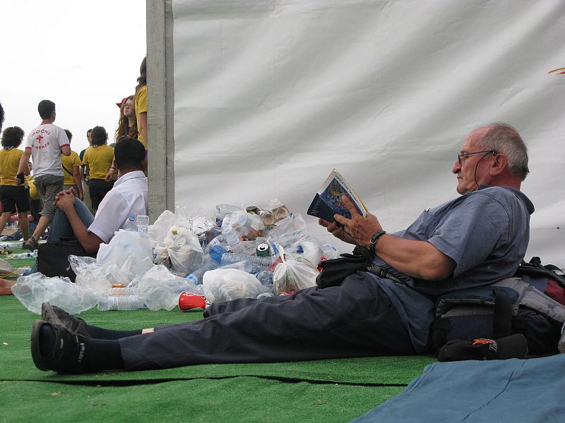 Un peregrino lee en Cuatro Vientos junto a una montaña de botellas de plástico vacías