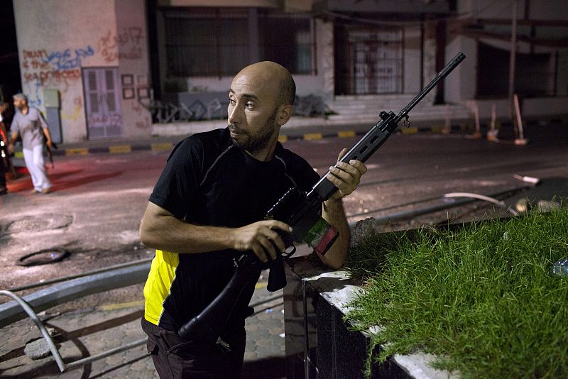 Rebelde avanzando en un punto de control la noche siguiente a la entrada de los opositores a Trípoli (Libia)