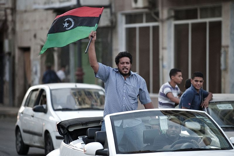 Un hombre ondea la antigua bandera libia, adoptada por los rebeldes, durante la celebración en Bengazi.