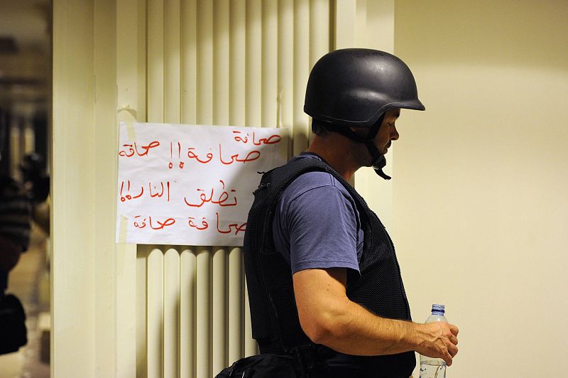 Periodista en un pasillo del hotel Rixos sobre un cartel en el que se puede leer: "No disparar, somos prensa"