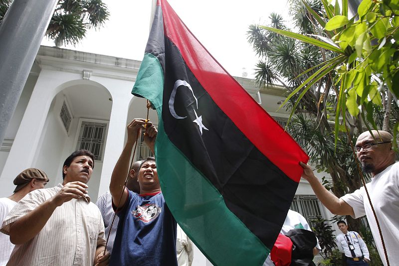 Un libio instala la bandera tricolor libia en el interior de la embajada de ese país en Manila (Filipinas)