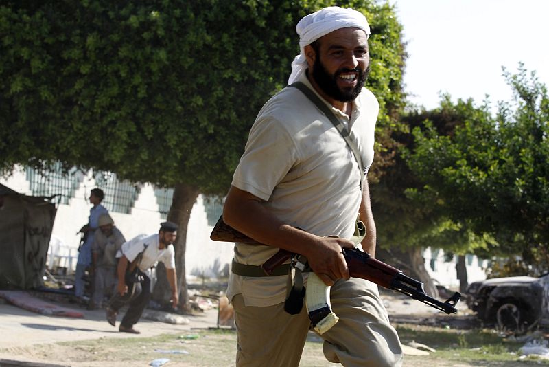 Un rebelde libio corre para ponerse a salvo durante los combates con fuerzas leales a Gadafi