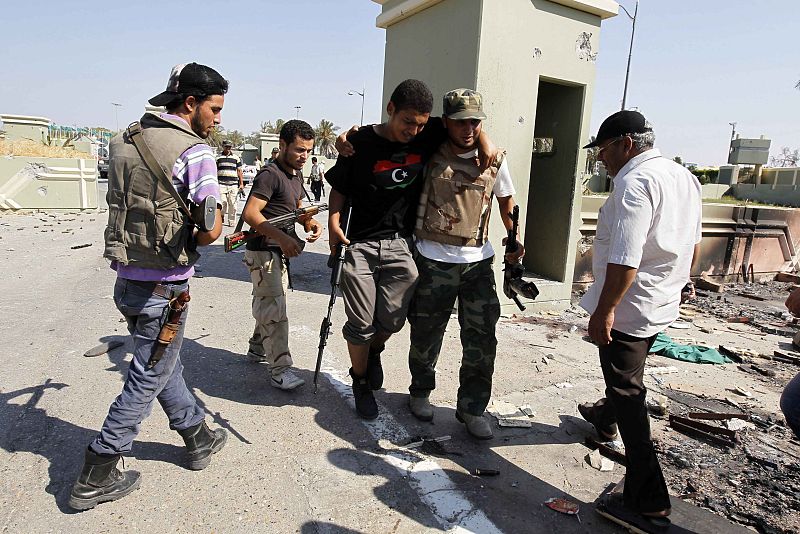 Un combatiente rebelde ayuda a un compañero durante los ataques en Trípoli