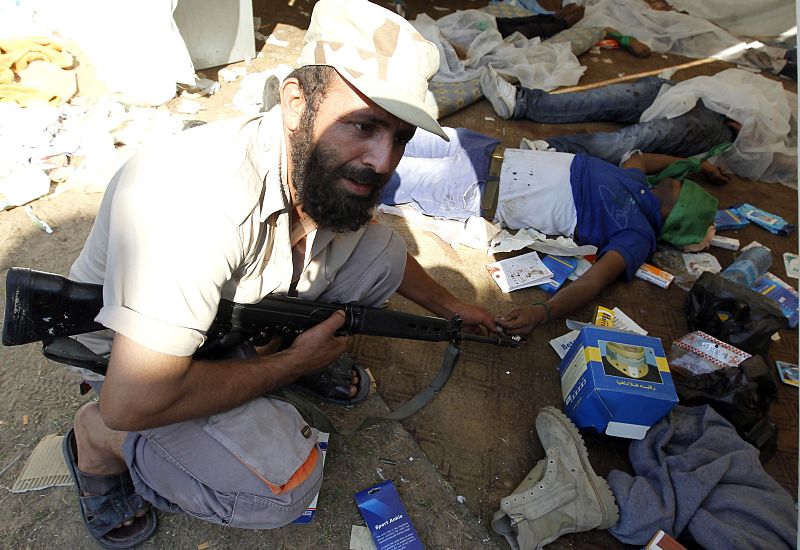 Un combatiente rebelde muestra los cuerpos de soldados leales a Gadafi en Trípoli