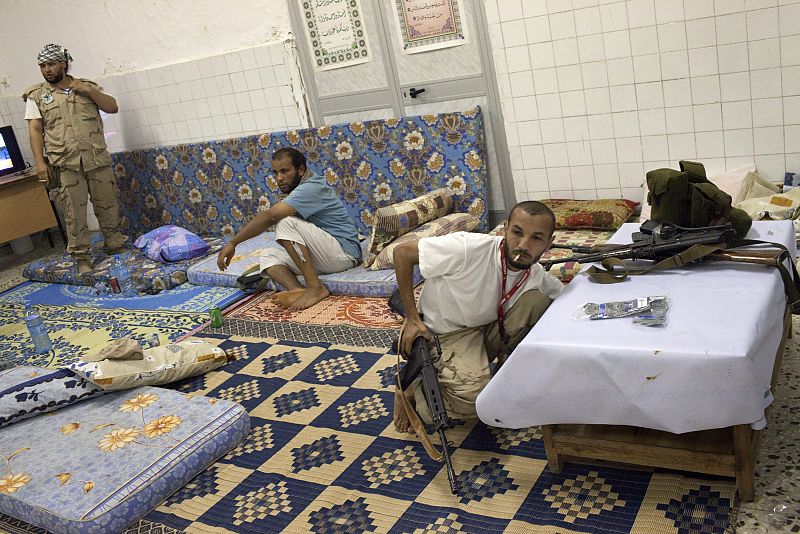 Rebeldes libios descansan durante en la sede de la brigada en Trípoli (Libia).