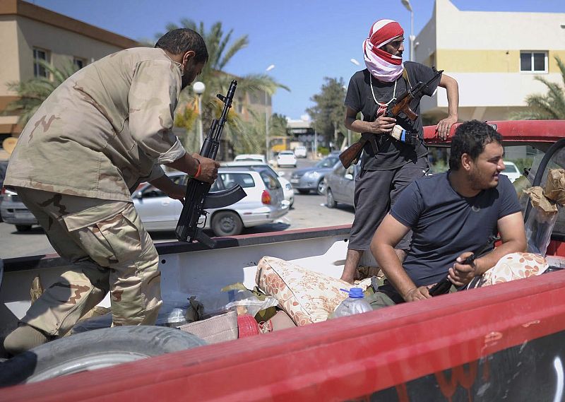 Combatientes rebeldes armados en la parte trasera de una camioneta "pickup" en una calle de Tripoli, Libia