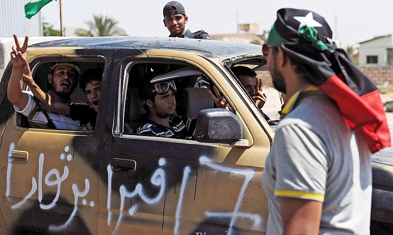 Rebeldes libios armados pasan por un puesto de control en Trípoli