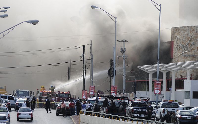 Un grupo de bomberos trata de apagar el incendio ocasionado tras el lanzamiento de granadas