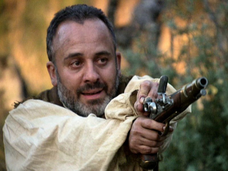 Incomprensiblemente, Sátur, sosteniendo un arma, amenaza con matar a Águila Roja.