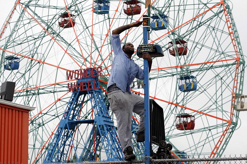 Carlos Wright works to take down a flag on the Coney Island boardwalk in preparation for Hurricane Irene in New York