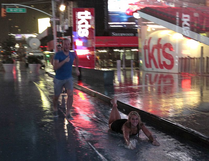 Una chica se divierte bajo la lluvia del huracán 'Irene'.