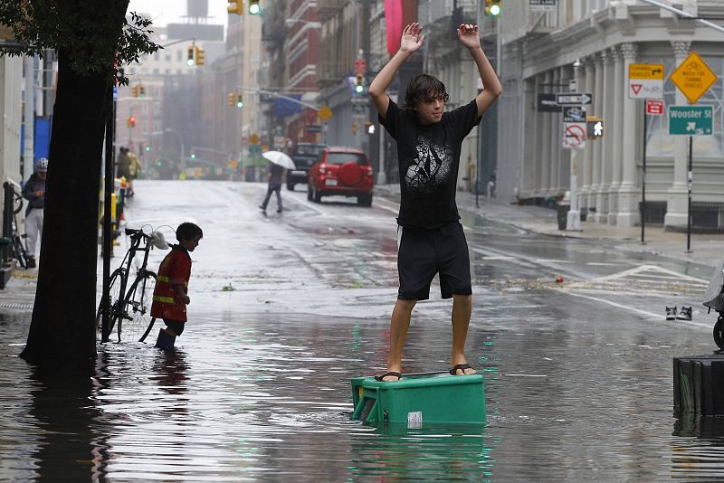 A boy stands on a newspaper box in a flooded street in the Soho section of Manhattan after Hurricane Irene passed over the New York City area