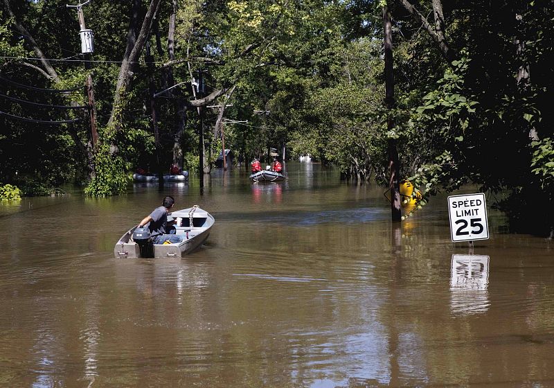 A man manoeuvres his boat near a rescue team through a flood caused by Hurricane Irene in Wayne, New Jersey