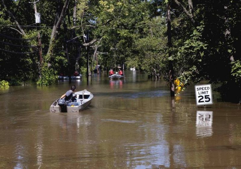 A man manoeuvres his boat near a rescue team through a flood caused by Hurricane Irene in Wayne, New Jersey