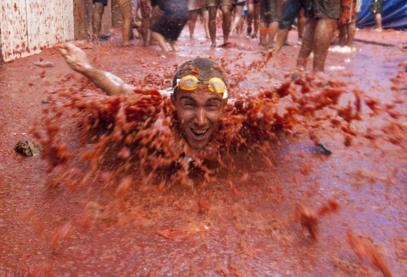 Un jóven nada en un auténtico río de tomate en Buñol  (Valencia) durante la tradicional Tomatina