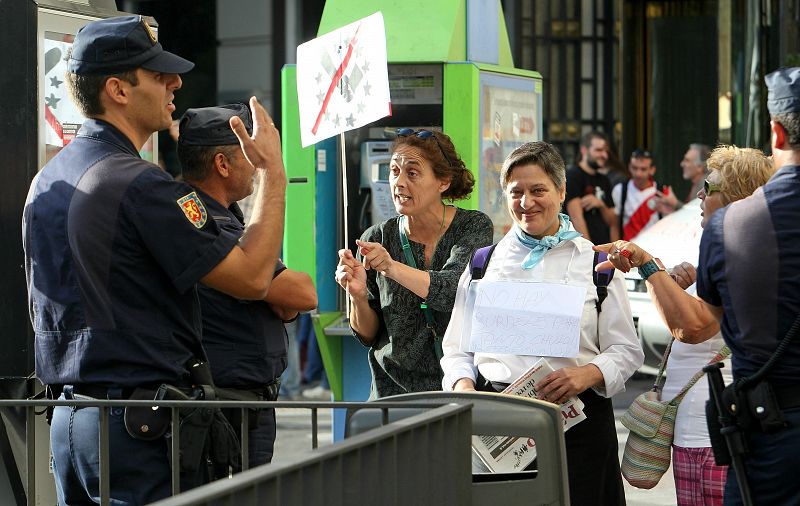 Agentes de la Policía Nacional, frente a un grupo de personas que se han concentrado a primeras horas de la mañana en la plaza de Neptuno