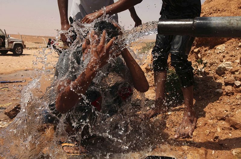 Soldado anti-Gadafi se refresca en las proximidades de Sirte, a 450 kilómetros al oeste de Bengasi