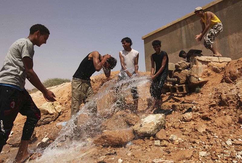 Proximidades de la ciudad de Sirte. Los soldados tratan de asearse con el agua que vierte una tubería.