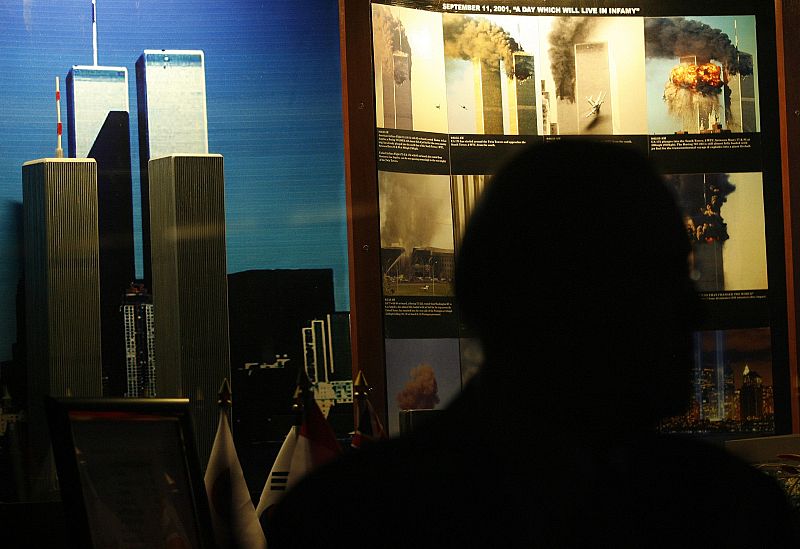 A U.S. man is silhouetted in front of a diorama of the 9/11 attacks on the World Trade Center, during a ceremony marking the 10th anniversary of attacks in Manila