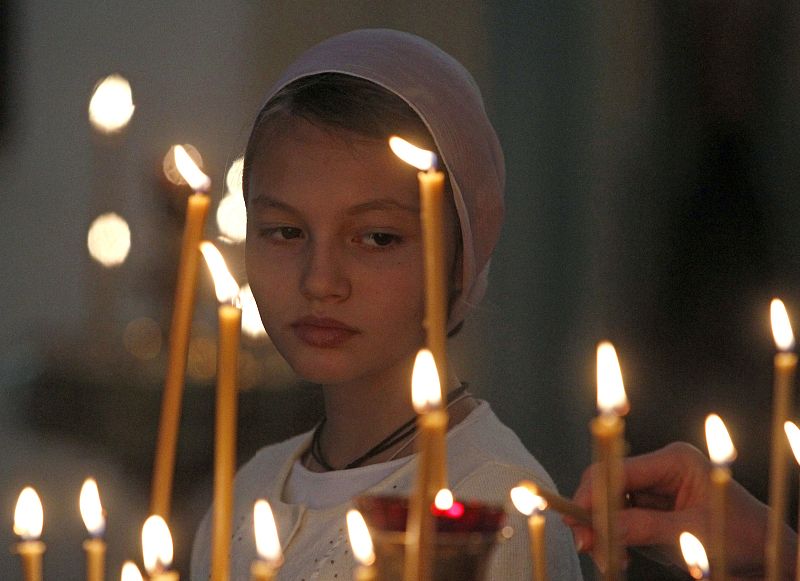 A woman watches candles being lit during an Orthodox service to commemorate the 10th anniversary of the 9/11 attacks, at a church in Moscow