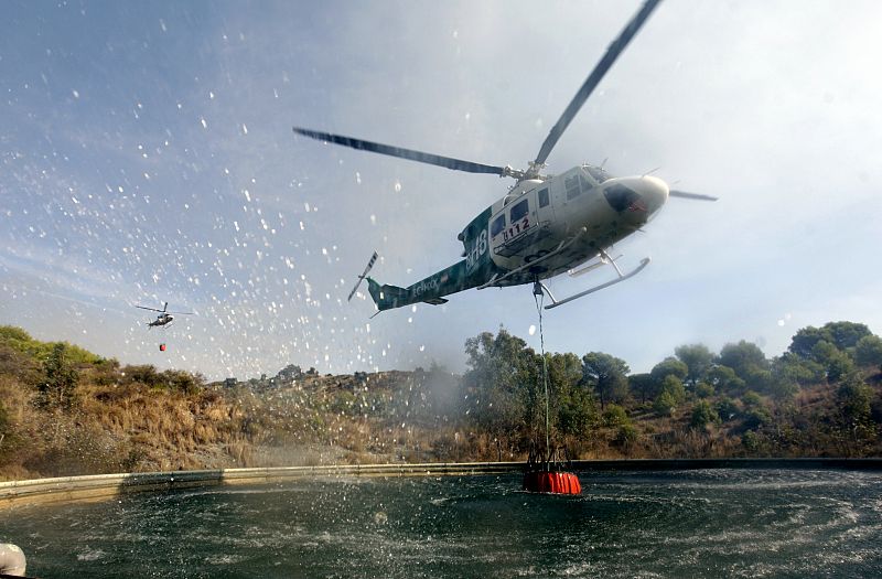Un helicóptero recoge agua de una de las piscinas durante las tareas de extinción