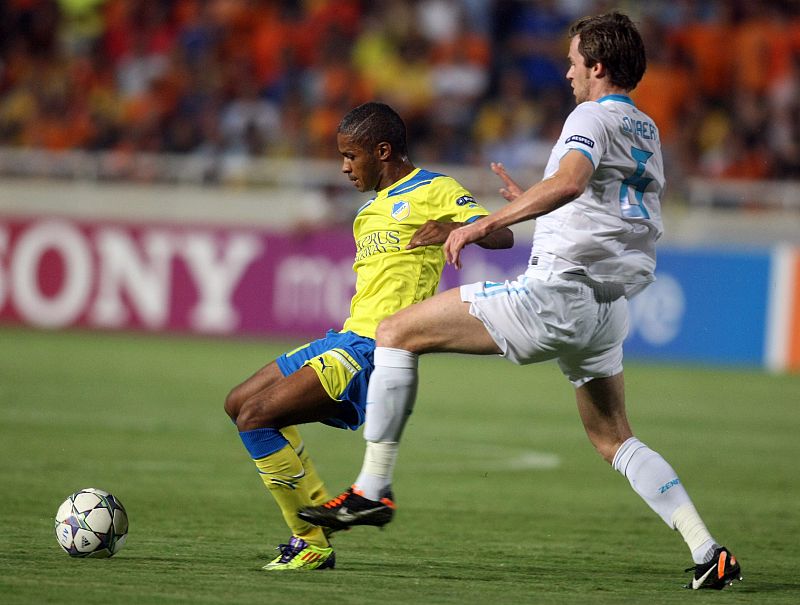 El jugador del Apoel Marcinho (i) se protege de la entrada de Lombaerts (d) en el APOEL Nicosia - Zenit San Petersburgo