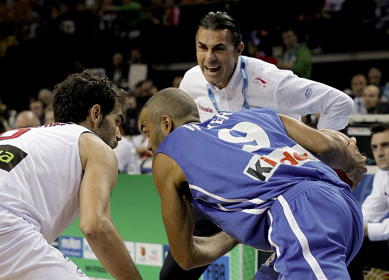 El base-escolta de la selección francesa Tony Parker (c), con el balón defendido por el escolta de la selección española José Calderón (i), mientras el español recibe instrucciones de su entrenador, Sergio Scariolo.