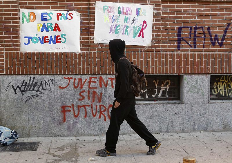 Un estudiante camina por delante de un cartel contra los recortes en la enseñanza pública