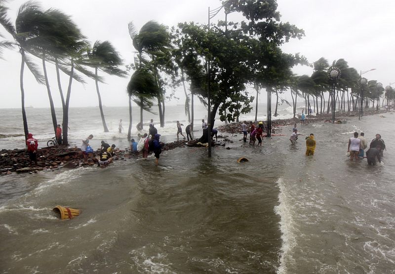 Filipinos caminan por el malecón de la calle Roxas destruido por el paso del tifón "Nesat" en Manila