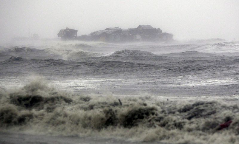 Olas gigantes chocan contra chabolas en el litoral de la Bahía Manila